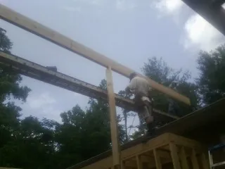 Carpenter setting a ridge beam over a new addition frame — Ice Dam Removal by Roofing Brothers in Finley