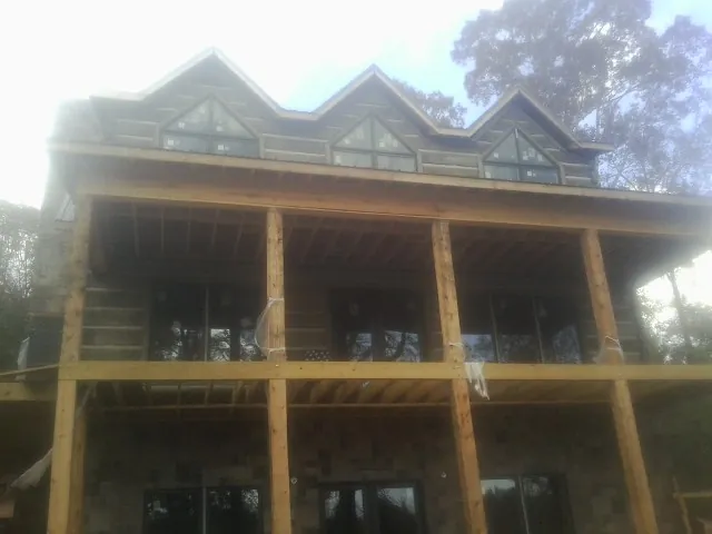 Dormers and porch framing on a large log home under construction — Roof Coating work by our crew in Finley