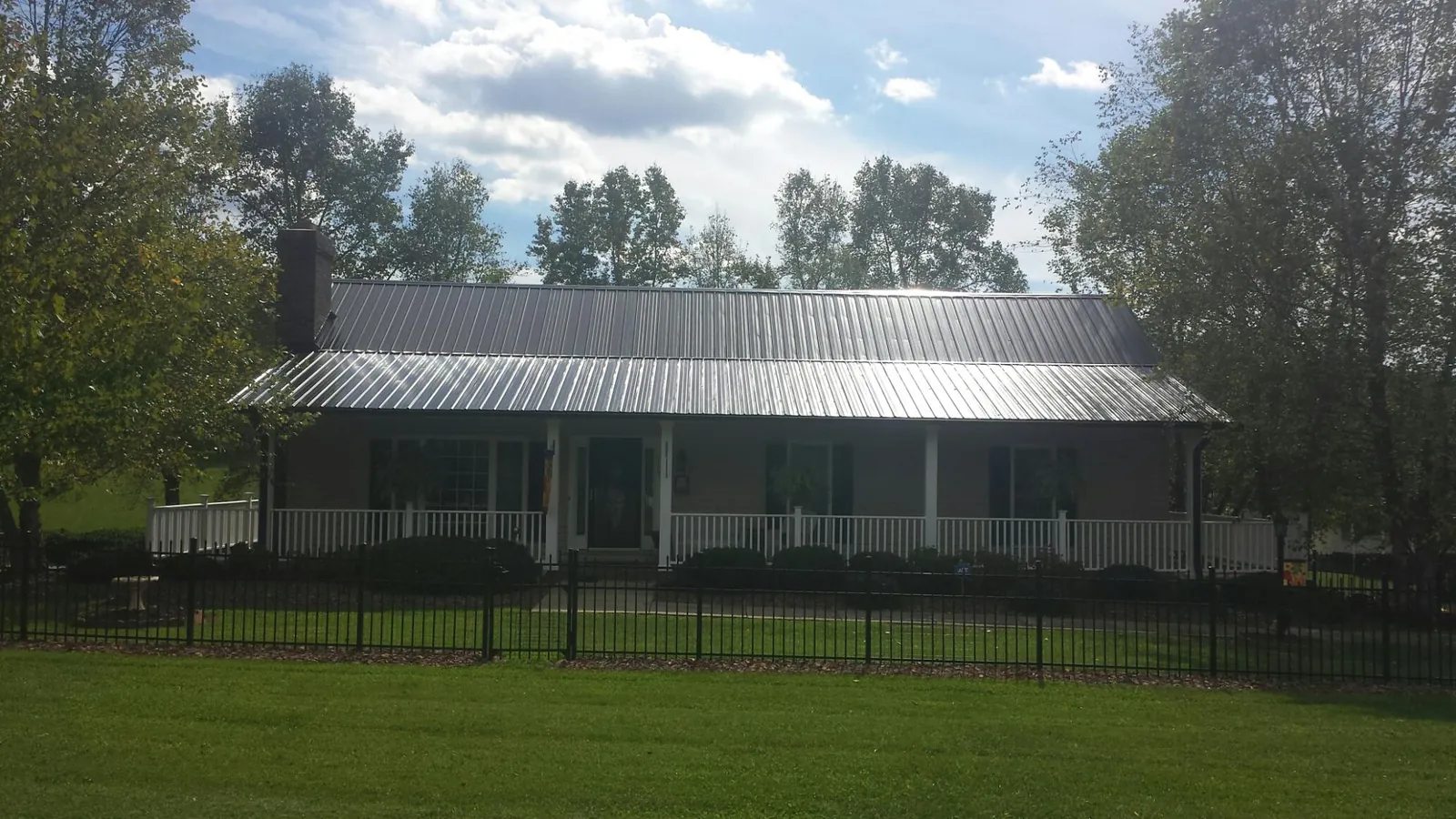 Gray metal roof on a brick ranch with a full width front porch — Gutter Guard Installation work by our crew in Finley